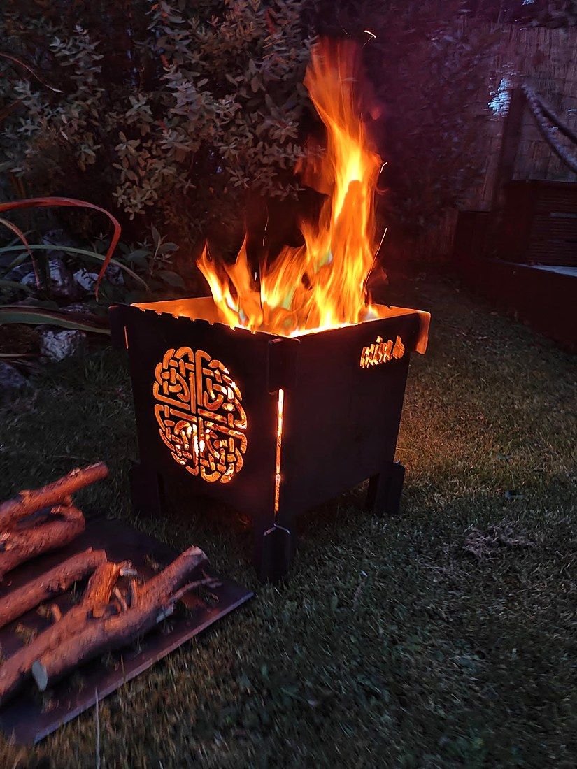 Celtic knot fire pit glowing at dusk in a garden